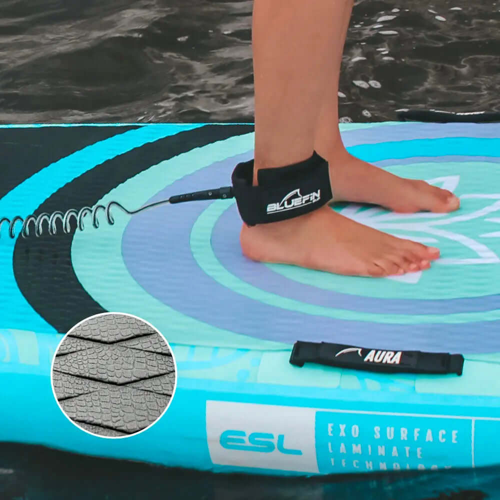 Personne debout sur un paddleboard gonflable bleu avec une laisse et un pad de pont texturé