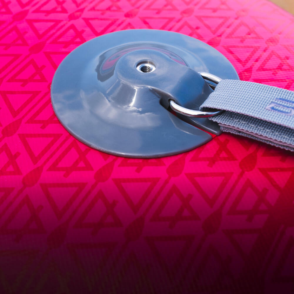 Inflatable paddleboard detail showing gray inflation valve and strap on pink patterned surface