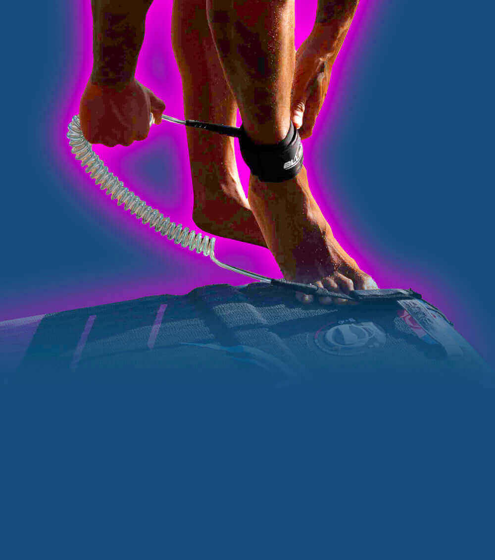Person attaching a coiled leash to their ankle while standing on a paddleboard
