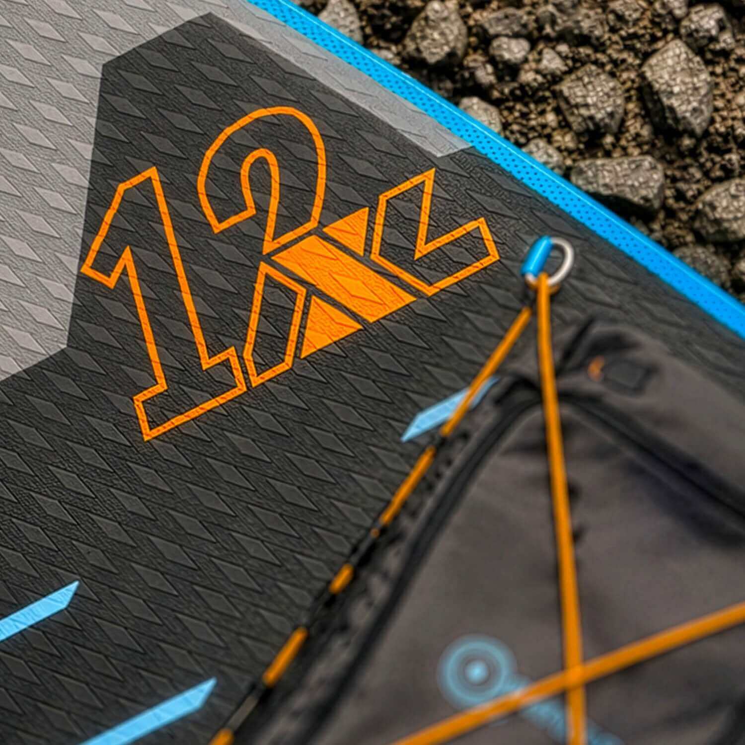 Close-up of a textured paddleboard deck featuring the number 12 and orange accents.