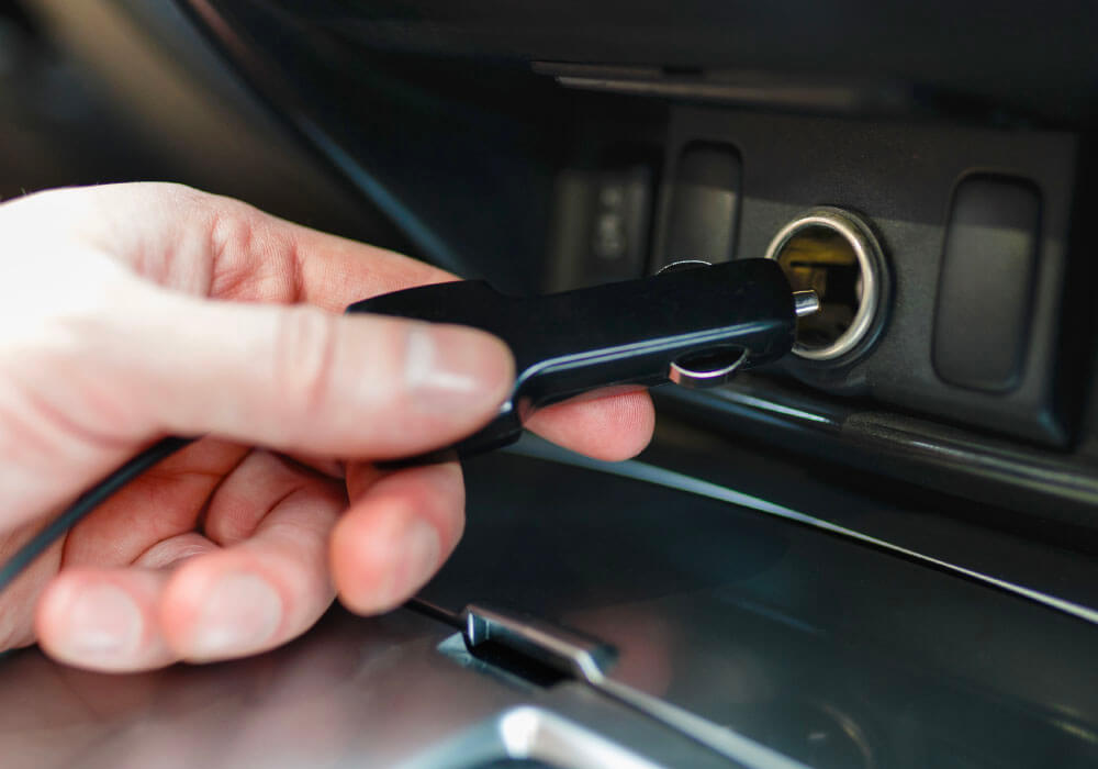 Hand inserting a black car key into the ignition socket of a vehicle's dashboard