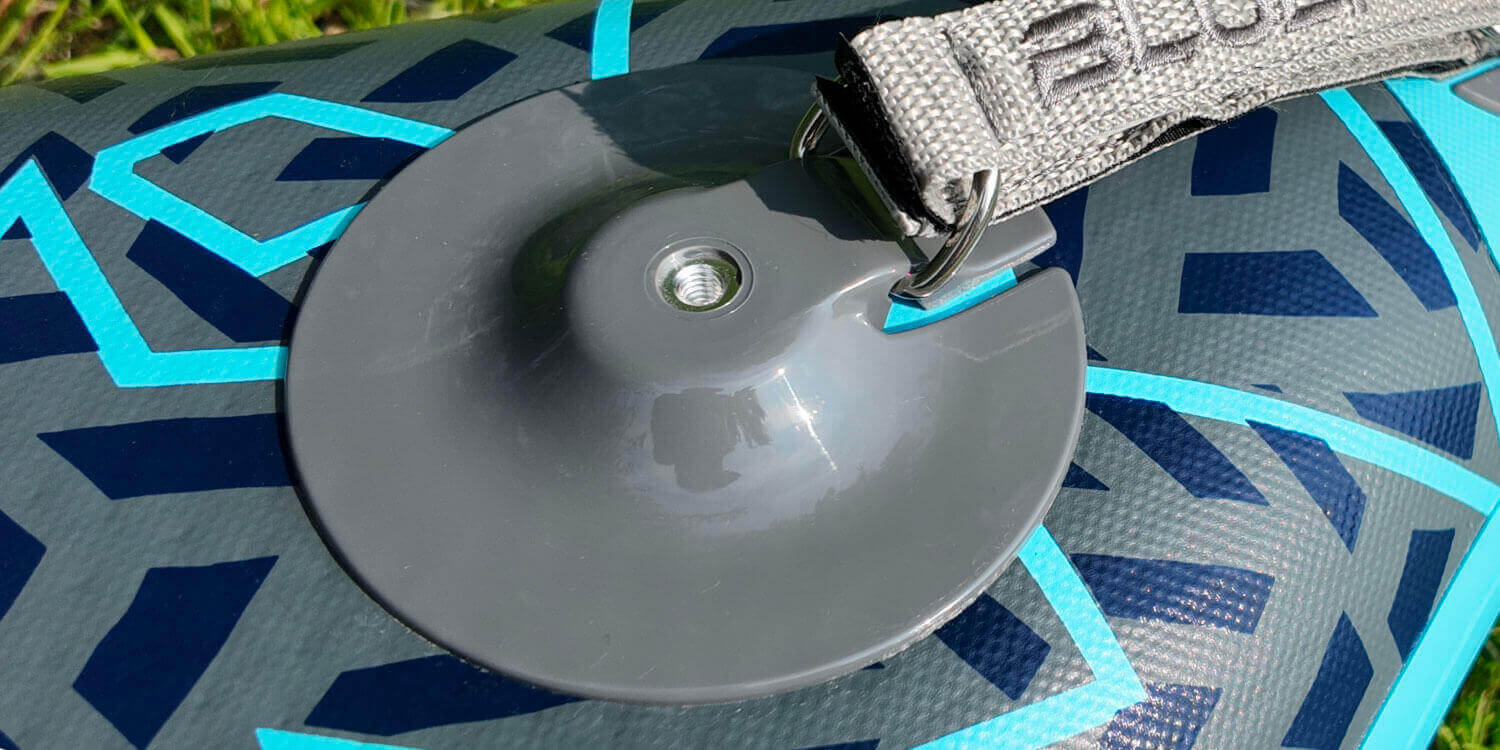 Inflatable paddleboard showing a gray fin attachment and a gray inflation valve on the surface