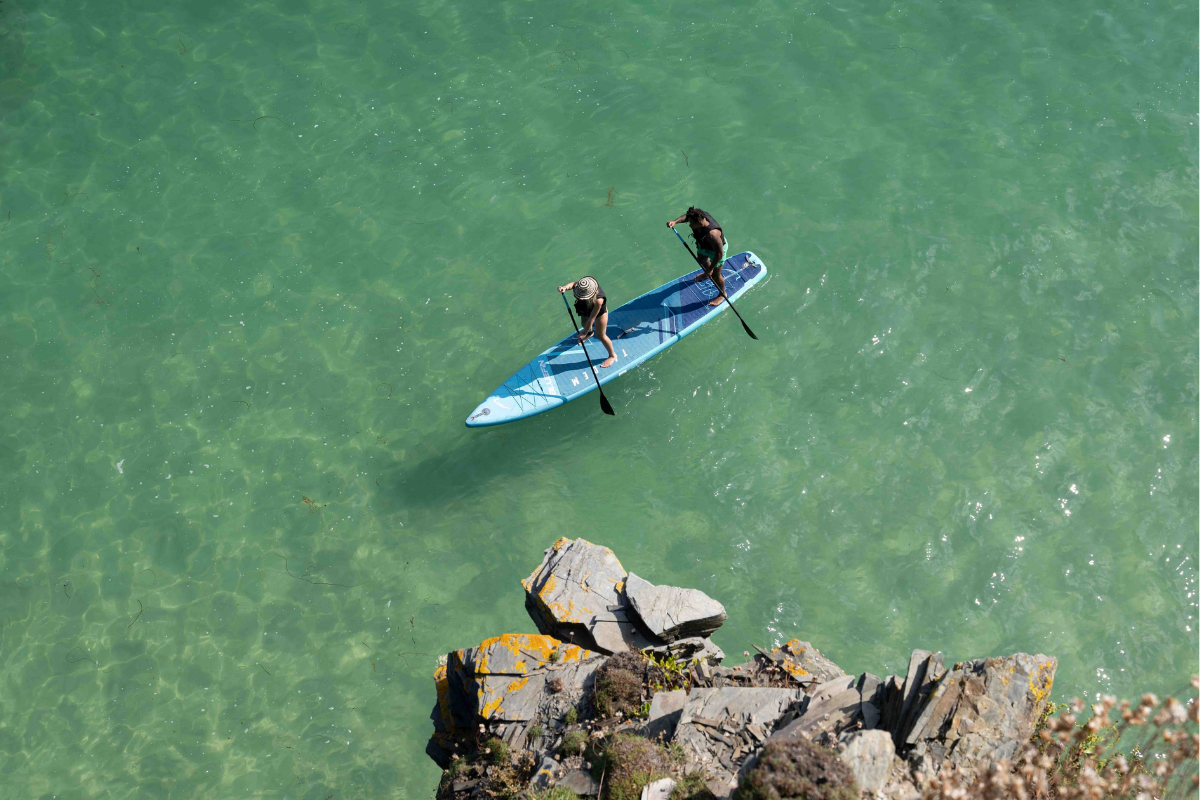 two people on a tandem paddleboard in the ocean