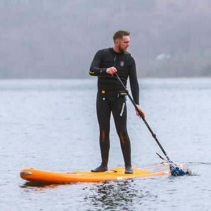 Mann im Neoprenanzug paddelt auf einem orangefarbenen Stand-Up-Paddleboard im ruhigen Wasser.