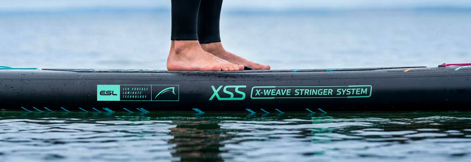 Inflatable paddleboard with feet on deck, featuring X-Weave Stringer System and Exo Surface Laminate Technology