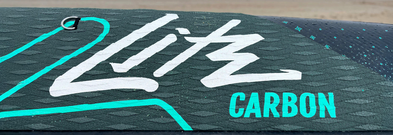 Textured paddleboard deck with white "Litz" logo and "CARBON" in turquoise lettering