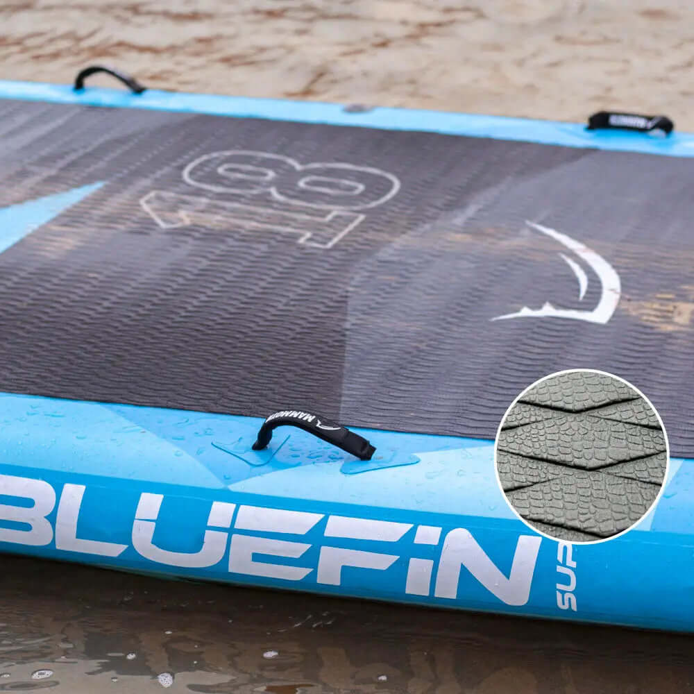 Aufblasbares Paddleboard mit strukturiertem Deck, blauen Kanten und Mittel-Finne auf nassem Sand
