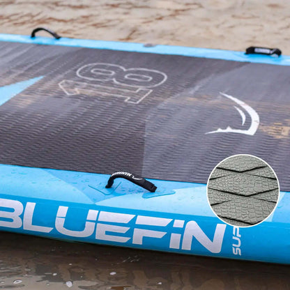 Aufblasbares Paddleboard mit strukturiertem Deck, blauen Kanten und Mittel-Finne auf nassem Sand