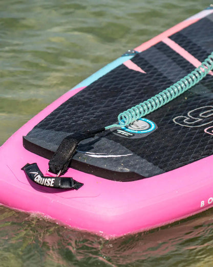 Inflatable paddleboard with pink edges, coiled leash, and textured deck pad on water surface